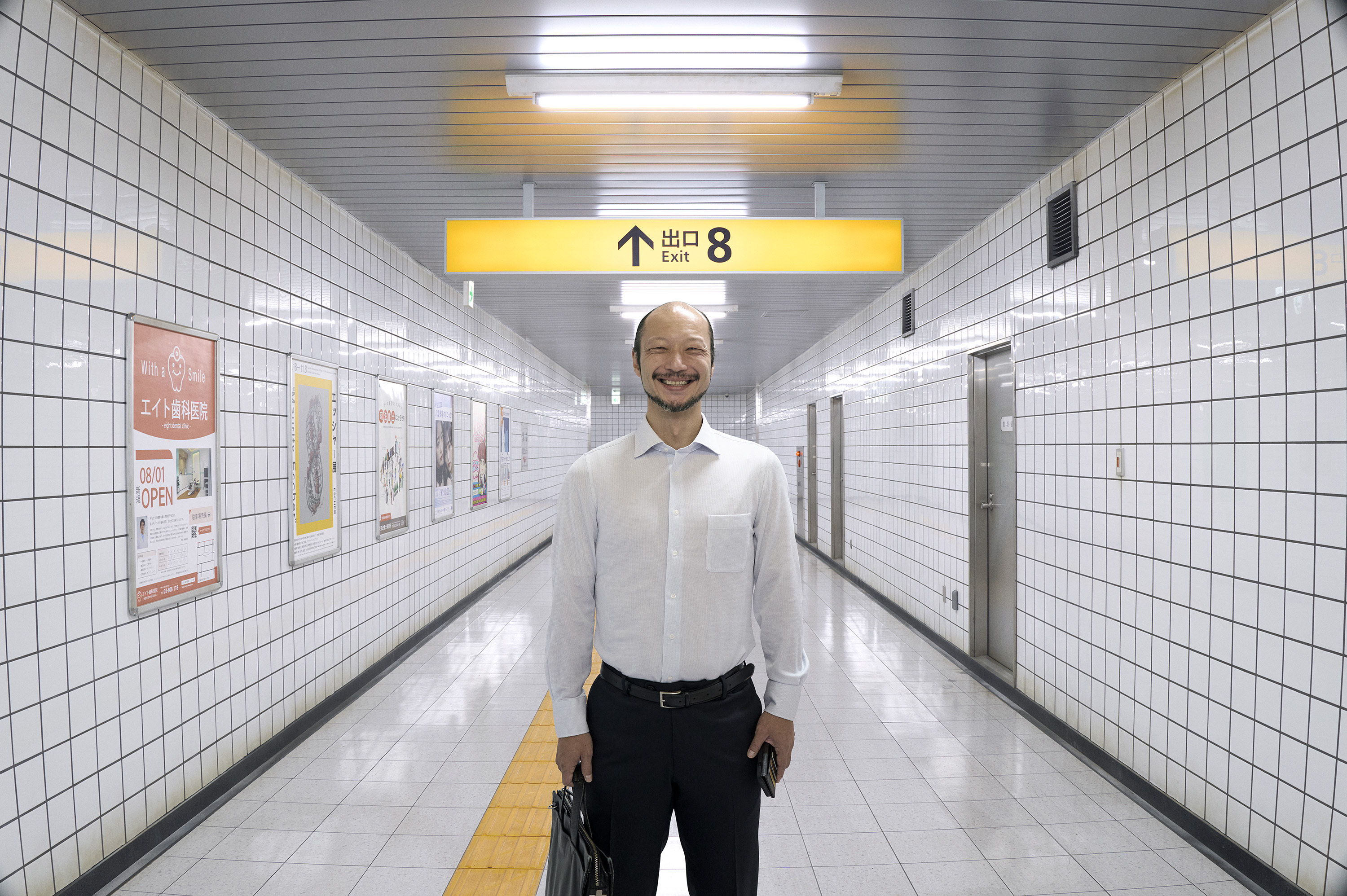 흰 타일과 안내 표지가 반복되는 Exit 8의 지하철 통로