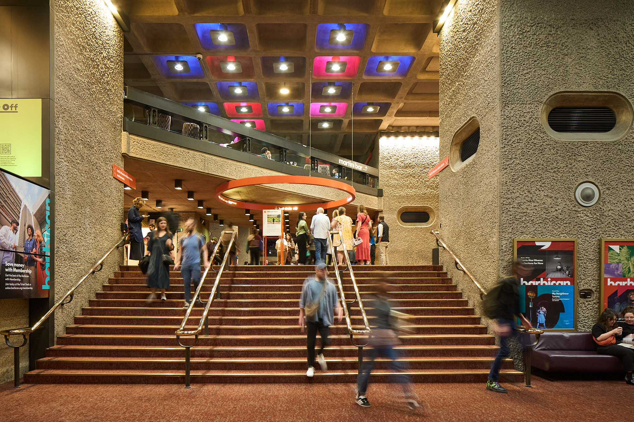 거친 콘크리트 기둥과 계단, 격자 천장이 겹치는 Barbican 내부 로비