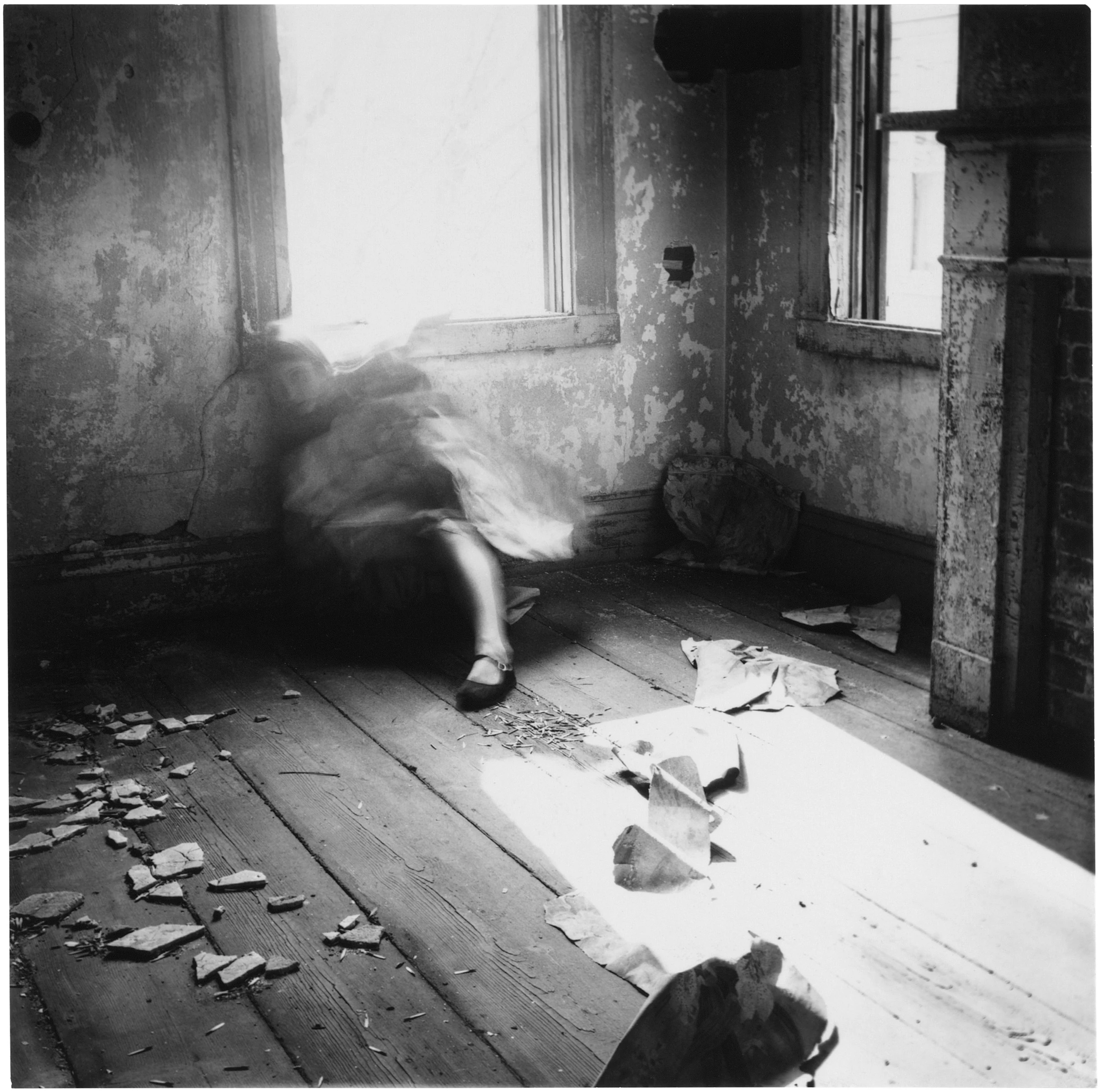 벗겨진 벽과 벽난로 앞에서 장노출된 몸이 흐려지는 Francesca Woodman의 House #3